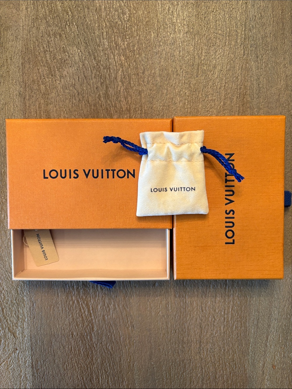 Two Louis Vuitton Orange Boxes and one Cream Drawstring Pouch with Blue Cord.